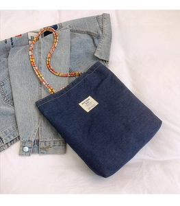 Détail du cabas en jean bleu avec anses tressées colorées et étiquette tissée sobre