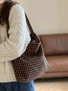 Lifestyle shot of a retro brown plaid wool tote bag worn as a shoulder bag