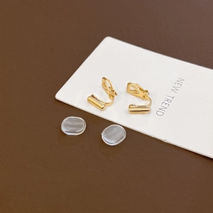 Macro detail of gold adjustable screw earring converters with silicone pads on a card