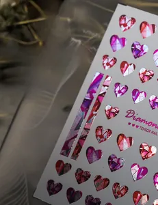 Macro detail of laser metallic heart nail art stickers with ruby and purple gemstones