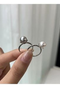 Dettaglio di anelli regolabili in argento S925 con perle grigie e bianche sulla mano