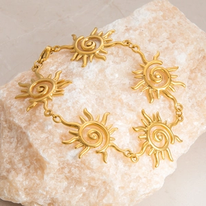 Detailed close-up of golden sun-shaped links bracelet with spiral design on stone