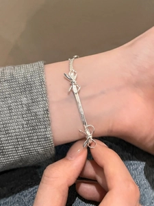 Close-up of a silver bow-knot herringbone chain bracelet worn on a female wrist