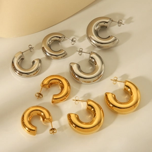 Close-up of gold and silver thick hoop earrings with polished metal texture