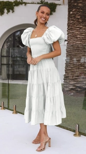 Close-up of a white puff sleeve summer dress with tiered cake skirt and pleated waist