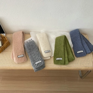 Solid color narrow knit scarves in pink, grey, beige, green and blue on a bench