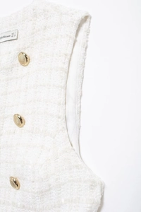 Detail of white tweed vest featuring golden buttons and internal brand size label