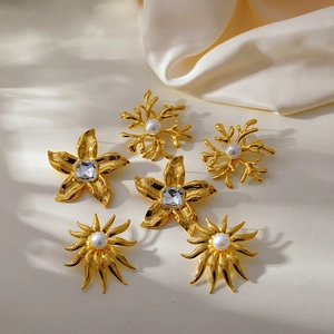 Detail of three pairs of gold flower and coral geometric earrings with pearls