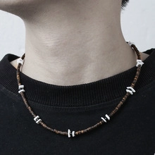 Close-up of men's necklace with natural dark wood beads and white stone on male model