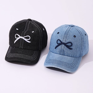 Detail shot of denim baseball caps in black and light blue with bow embroidery