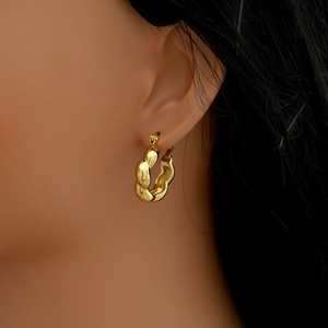 Close-up of gold twist hoop earring with textured rope pattern on female model ear