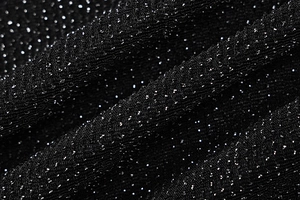 Macro shot of black metallic fabric with silver glitter and soft texture folds