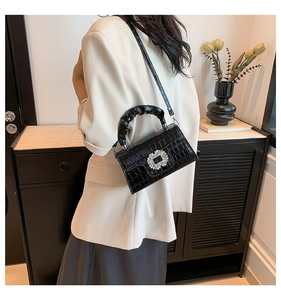 Détail du sac noir motif crocodile avec boucle carrée en cristal et poignée plissée