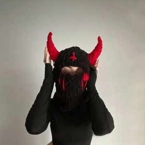 Detail of knitted balaclava with red devil horns and cross embroidery for Halloween