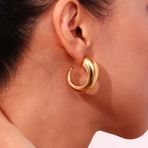 Close-up of chunky gold C-shaped horn hoop earrings with polished stainless steel finish