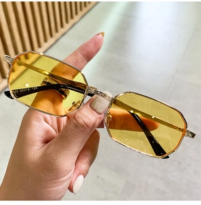 Macro shot of polygonal metal sunglasses featuring yellow lenses and detailed gold temples