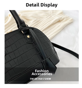 Close-up of black crocodile embossed shell bag featuring golden zipper and rivets