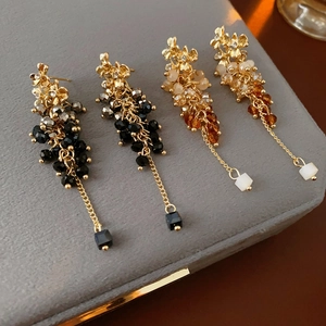 Detail of luxury flower tassel earrings with hanging chains and colorful square pendants