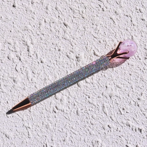 Detailed close-up of a rose gold pen featuring iridescent rhinestones and a purple crystal ball