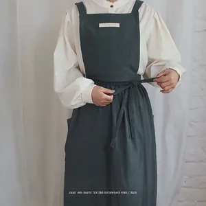 Dark green cotton apron with wide straps and large front pockets for kitchen use