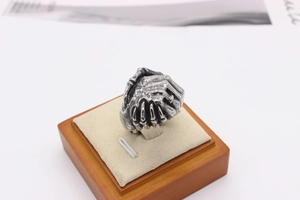 Detailed close-up of retro silver skeleton hand ring on a beige velvet jewelry tray