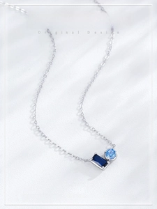 Macro shot of silver pendant necklace featuring square and round blue sapphire gemstones