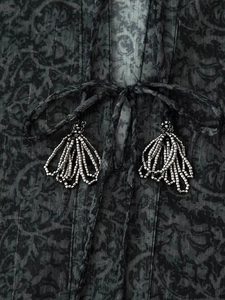 Detailed close-up of dark chiffon fabric with metallic bead tassels and textured prints
