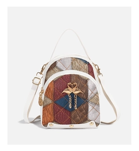Détail du sac à dos patchwork multicolore avec pendentif cygne doré et clous métalliques