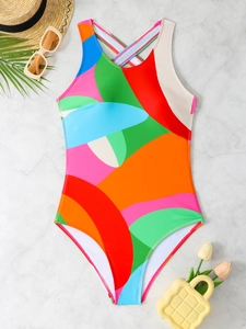 Flat lay of colorful geometric kids swimsuit with cross-back straps and beach accessories