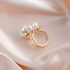 Detail of elegant gold ring with two white pearls on soft pink satin background
