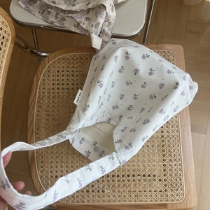 Detail of floral cotton shoulder bag with metal snap button and simple wish label