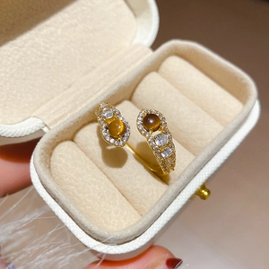 Detail of gold snake-style open ring with brown tiger eye stones and zircon accents