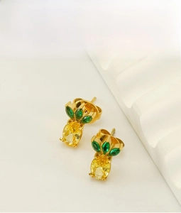 Macro detail of gold pineapple stud earrings with green and yellow zircon crystals