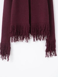 Detailed view of heavy knit wine red cardigan with layered fringe on hem and sleeves