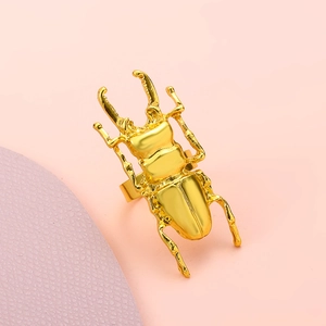 Detailed view of an oversized golden stag beetle ring with intricate metal textures