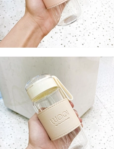 Detail of clear glass water bottle with beige leather sleeve and silicone handle