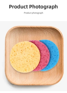 Detailed top view of three colorful round wood pulp sponges in a natural wood tray