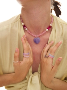 Macro shot of icy blue cat eye bead necklace with a purple heart pendant on a model