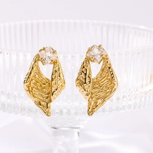 Irregular textured gold earrings with square zircon crystals displayed in glass