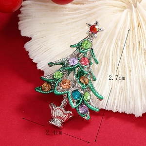 Sparkling Christmas tree brooch with colorful rhinestones on a festive red background