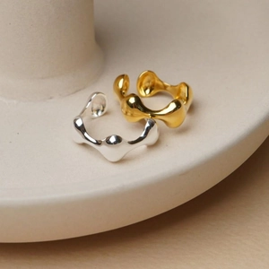 Close-up of gold and silver irregular liquid-style rings on a ceramic base