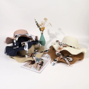Detail of elegant wavy brim straw hats with floral ribbons in various pastel colors