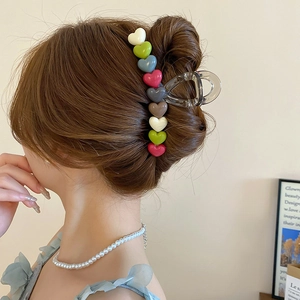 Detailed view of colorful heart-shaped hair claw clip styling a sleek updo for women