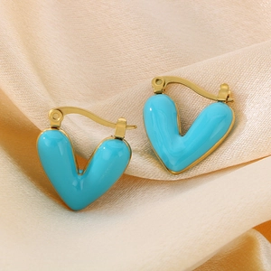 Macro shot of gold V-shaped earrings with vibrant blue enamel inlay on silk