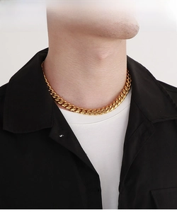 Close-up of a gold-toned chunky Cuban link chain necklace on a male model for hip hop style