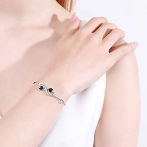 Elegant silver infinity bracelet with black heart charms and diamonds on a wrist