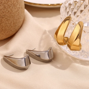 Detailed macro view of faceted hollow curved hoop earrings in gold and silver steel