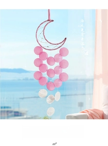 Detail of pink moon shell wind chime with translucent shell pieces and woven dreamcatcher net