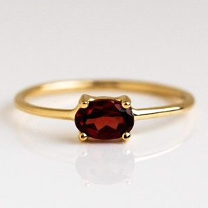 Macro shot of 18k gold plated ring featuring an oval deep red birthstone in a prong setting