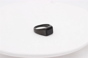 Macro shot of men's titanium ring featuring a rectangular black gemstone on a ceramic edge